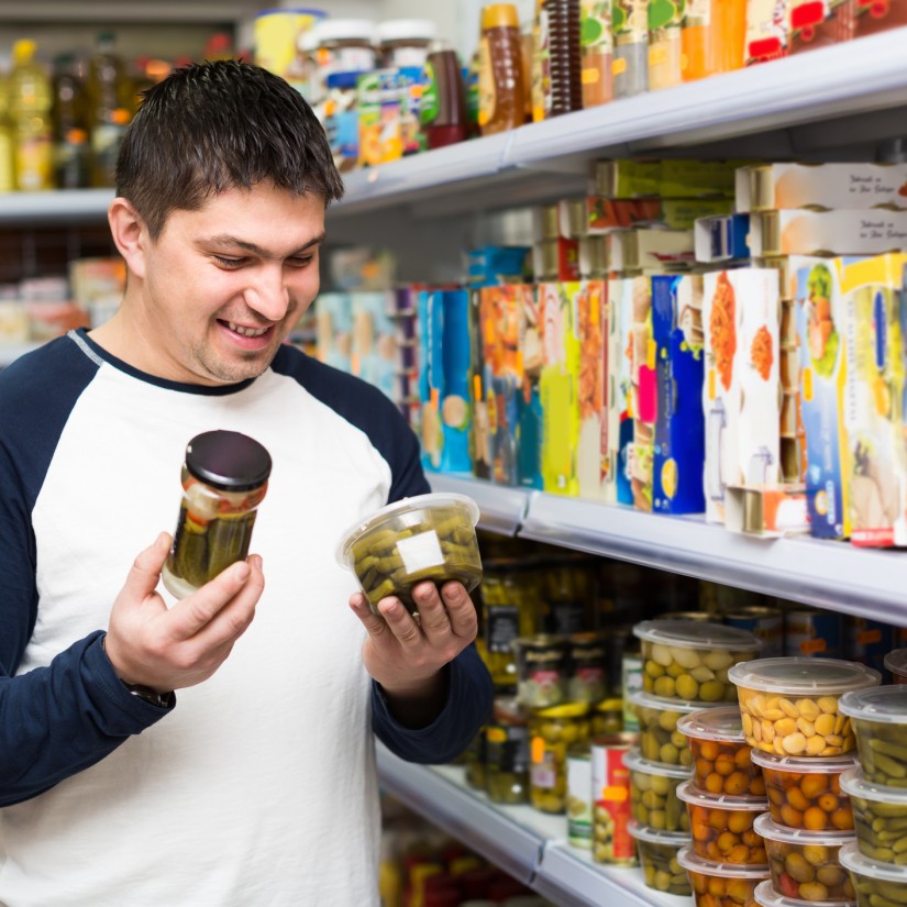 Ordinary guy buying tinned food at grocery store and smiling