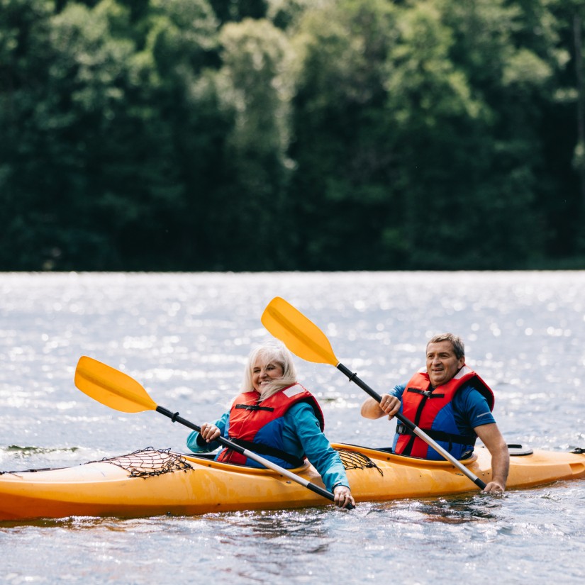 Happy senior active couple kayaking on lake enjoying time together